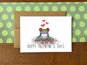 A note card with an illustration of a tree frog and red hearts with the message "Hoppy Valentine's Day!"